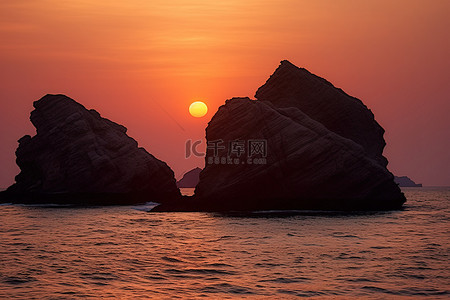 海中岩石背景图片_两块岩石，太阳在橙色的日落中落下