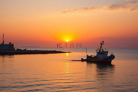 海岸防波堤背景图片_太阳从海岸的一艘渔船上升起