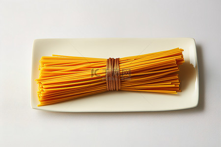 纸巾盒子样机背景图片_橙色和黄色的意大利面棒包裹并拴在纸巾上