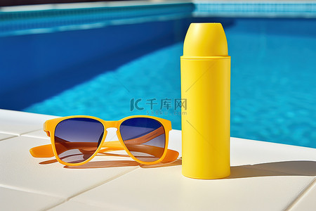 夏天泳池边的太阳镜和防晒霜瓶