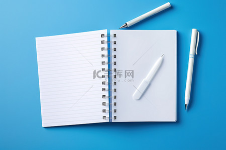 蓝色背景中打开笔记本笔和办公用品