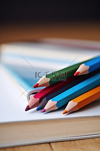 一支彩色铅笔背景图片_两支彩色铅笔放在一本书旁边，书打开了