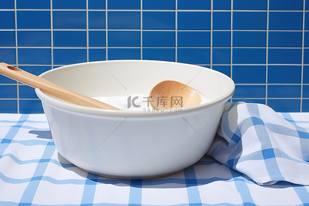 一把艾草背景图片_蓝色瓷砖背景中的一碗洗涤液旁边放着一把木勺