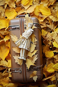 叶子旁边放着一个装有旅行雕像的白色手提箱