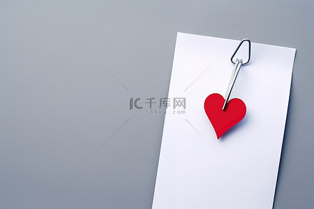 logo回形针背景图片_一个回形针，上面挂着一张纸，里面有一张心形的情书