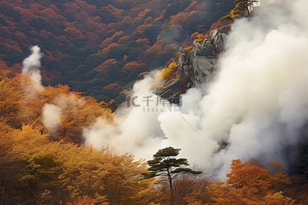 烟雾从覆盖着秋叶的山顶墙壁上倾泻而出