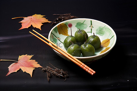 筷子传统背景图片_一个装满水果并用筷子和树叶装饰的碗