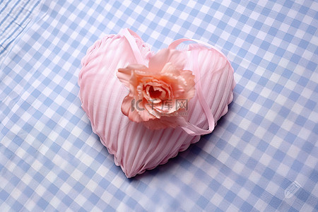 情人节花朵装饰背景图片_一朵心形的粉红色花朵坐落在白色格子桌布上