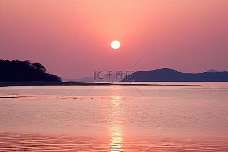 照耀背景图片_粉红色的太阳照耀着岛屿附近的浅海