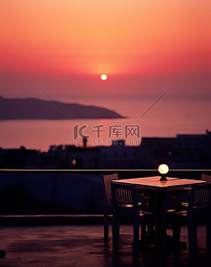 希腊太阳背景图片_太阳落山时，两个男人坐在外面的桌子旁的椅子上
