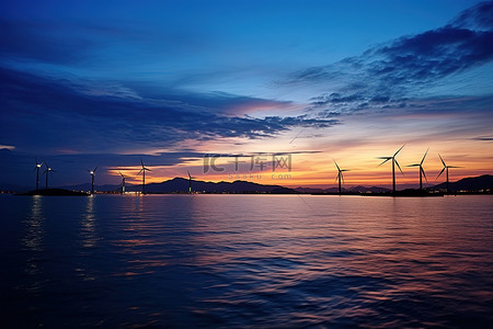 远处枯木背景图片_日落时的风力涡轮机和远处的一些岛屿