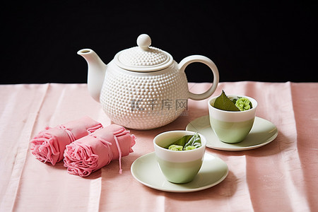 茶袋包装背景图片_白桌布的茶壶靠近两杯玫瑰和一套茶袋