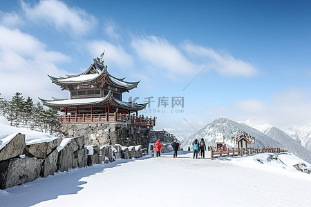 一座被雪覆盖的大山，有一个木制凉亭，旁边站着穿着滑雪服的人