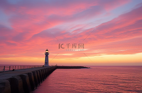 日落时码头和灯塔上空的粉红色天空