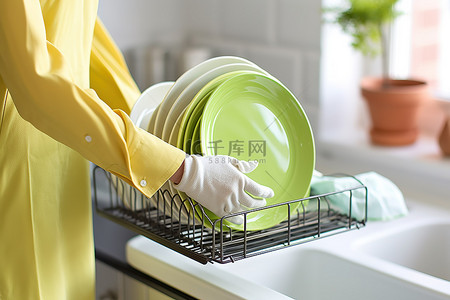 一名戴着工作手套的妇女从清洗架上取出几块盘子
