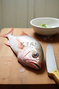 一张鱼坐在刀旁边的木桌上的照片