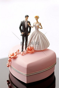 一对夫妇拿着白色和粉色心形盒子里的婚礼雕像