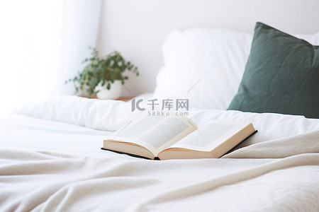 一本书放在一张带枕头的白色床上