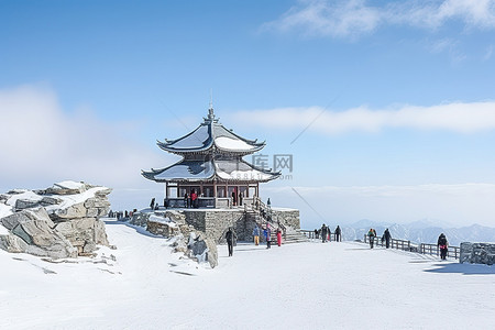 冬天的人背景图片_一座被雪覆盖的大山，有一个木制凉亭，旁边站着穿着滑雪服的人