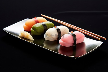 筷子和寿司背景图片_红色和黄色的筷子，上面有寿司，还有一个黑色的盘子