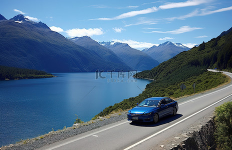 一辆蓝色轿跑车行驶在水背景旁，背景是山脉