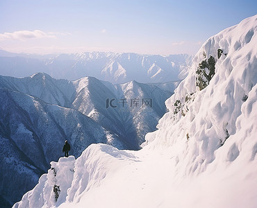 一个男人站在白雪覆盖的悬崖边山旁