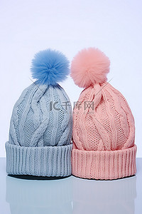 两顶带有蓝色和粉色绒球的针织无檐便帽