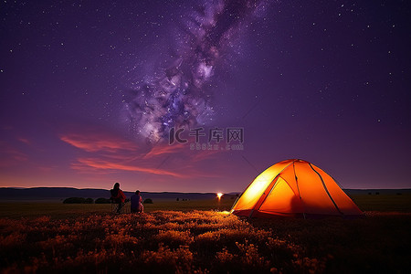 人们在营地附近的一片带有帐篷的田野里在星空下露营