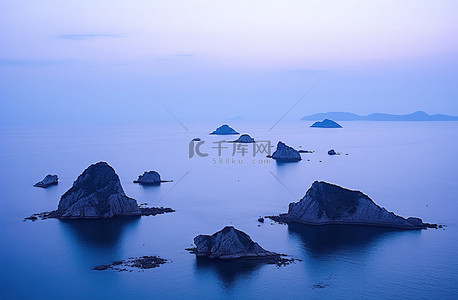 海上的岩石背景图片_夜晚的岛屿景色，水中有几块蓝色的岩石