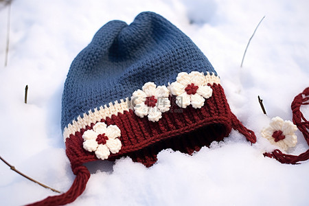 开蓝色背景图片_一顶蓝色无檐小便帽躺在雪地上，开着白花