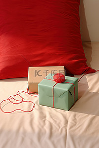 圣诞温暖背景图片_桌子上放着一个未完成的圣诞盒子，床上放着红纱
