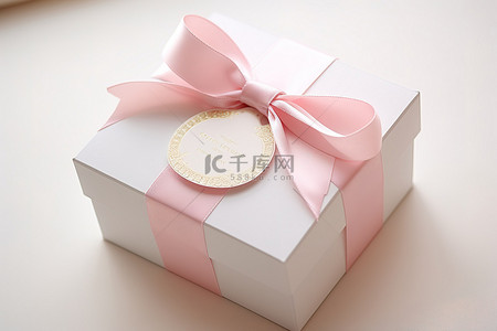 一个白色盒子，上面有一条粉红色丝带和一个标签
