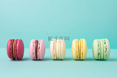 食物蛋白背景图片_薄荷绿色背景上排列在一起的五个彩色蛋白杏仁饼干