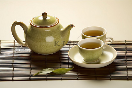 一个绿茶壶两个杯子和一些叶子