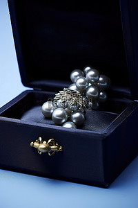 礼物盒黑背景图片_日本珍珠戒指，蓝盒内镶有黑珍珠