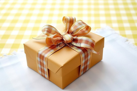 黄色礼物盒子背景图片_一个带蝴蝶结的黄色盒子放在格子桌布上