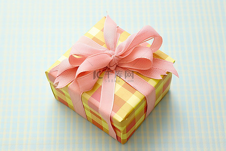 黄色小丝带背景图片_方格布上有黄色和粉色丝带的小礼盒