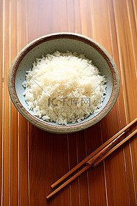 米饭筷子背景图片_用筷子在木桌上的小碗里盛米饭