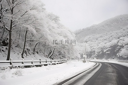 冬天街道背景图片_树木和雪山旁边的路上有雪