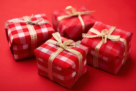 圣诞节格子背景图片_三件装饰过的红色礼物放在红色格子桌布上