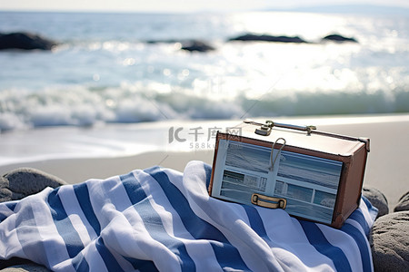 杂志背景图片_它在海滩上的毛巾旁边展示了一本书