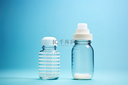 婴儿蓝色背景背景图片_蓝色背景中两个旁边有瓶盖的瓶子