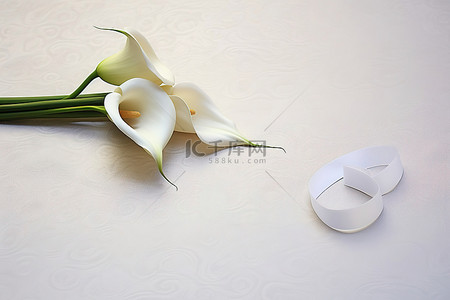 丝带婚礼背景图片_白桌上的婚礼马蹄莲，上面有一张卡片