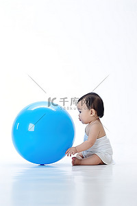 坐着婴儿背景图片_一个婴儿坐在白色的地板上，手里拿着一个蓝色的气球，试图让它飞走