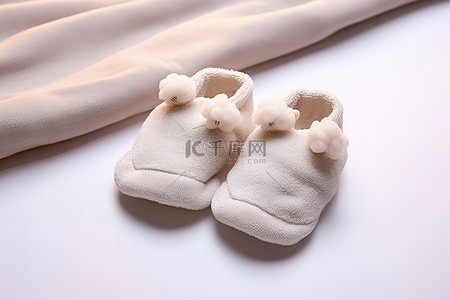 白色婴儿拖鞋坐在棉毯上