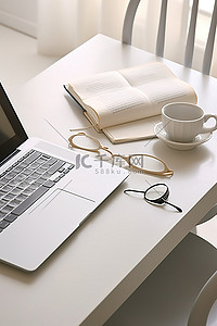 白色桌面上的一台笔记本电脑和一本书