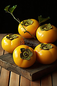 四个黄柿子坐在一张木桌上