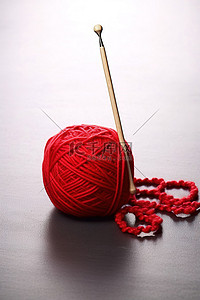 红色针织背景图片_有两个红色毛线球，上面有一个红色钩针