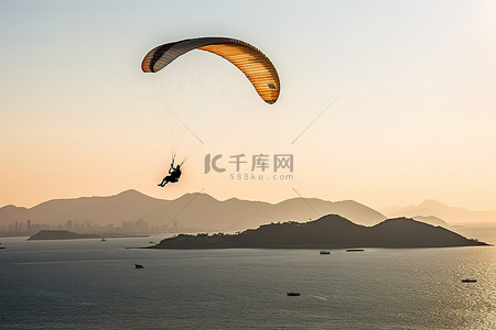 滑翔伞手绘背景图片_在海洋附近滑翔伞，背景是山脉