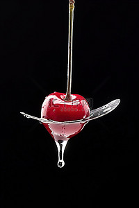 爱要大声出来背景图片_勺子上的樱桃，水从勺子里流出来
